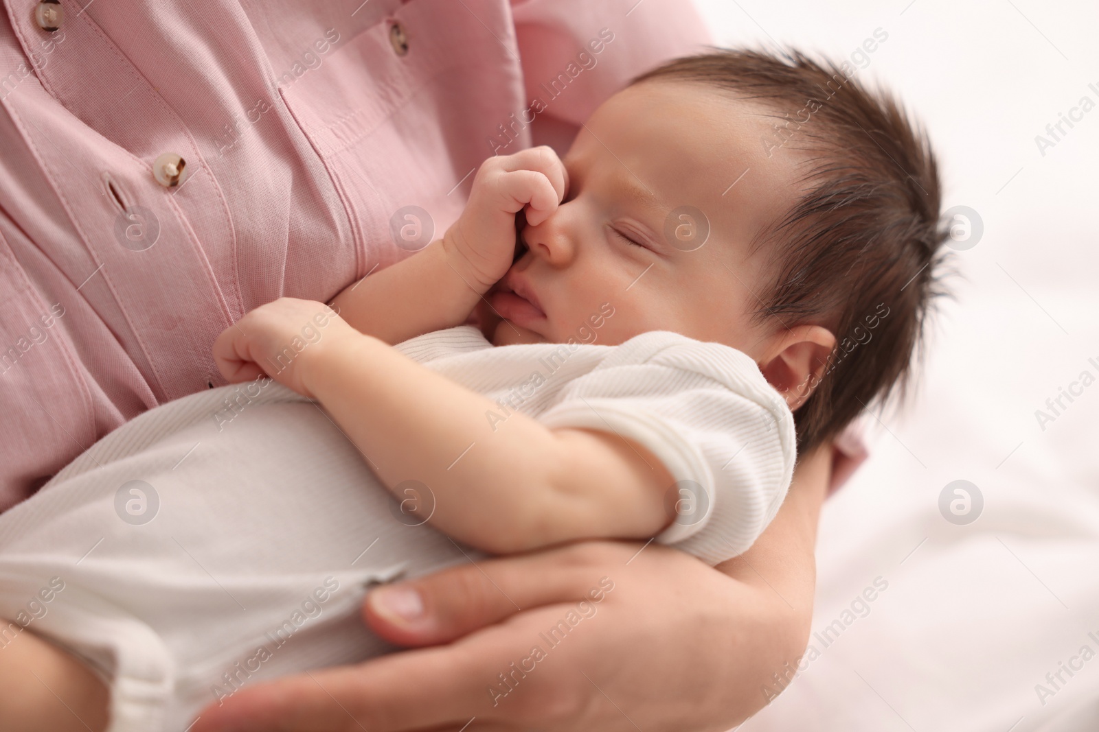 Photo of Mother with her sleeping newborn baby on bed, closeup