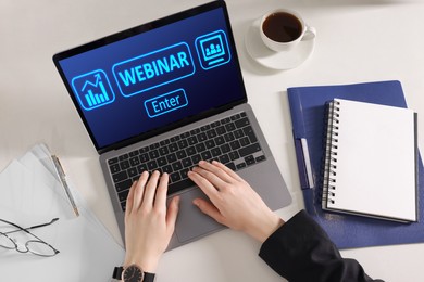 Online webinar, web page on computer screen. Woman using laptop at white table, above view