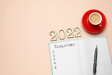 Making new year's resolutions. Notebook, cup of coffee and 2022 numbers on beige background, flat lay
