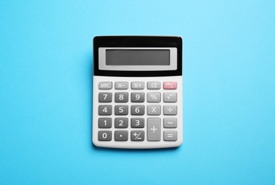 Calculator on light blue background, top view. Office equipment