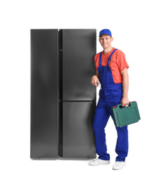 Male technician with tool box near refrigerator on white background