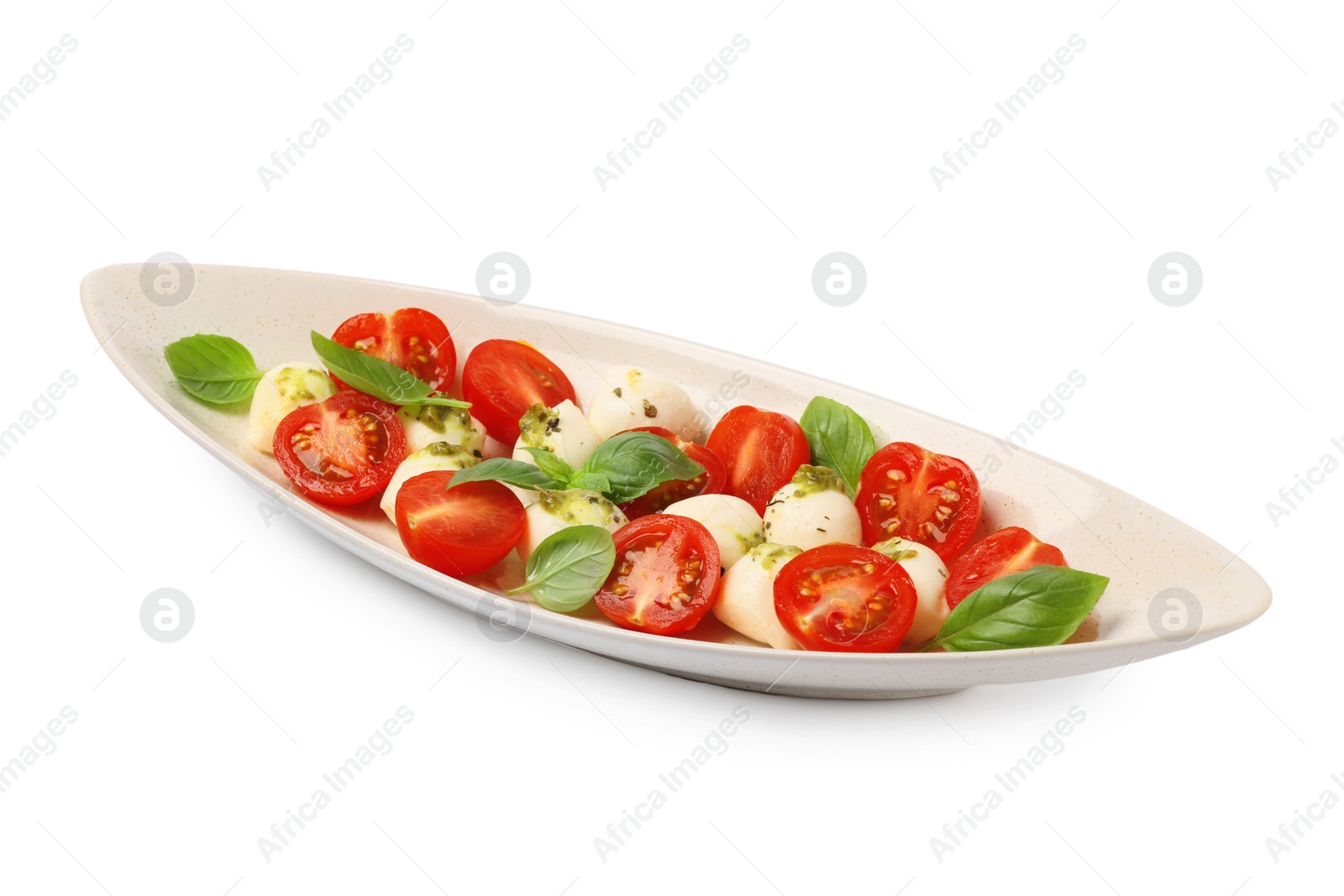 Photo of Plate of tasty Caprese salad with mozzarella, tomatoes, basil and pesto sauce isolated on white