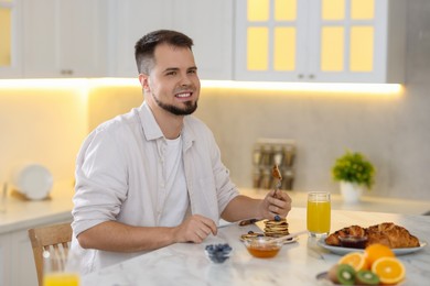 Photo of Smiling man having tasty breakfast at home