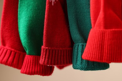 Photo of Different Christmas sweaters hanging on rack, closeup
