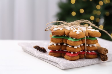 Photo of Decorated cookies on white table against blurred Christmas lights, closeup. Space for text
