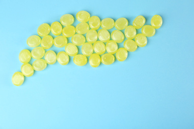 Photo of Delicious lemon drops on light blue background, flat lay. Space for text