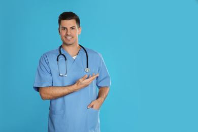 Photo of Handsome doctor with stethoscope on blue background. Space for text