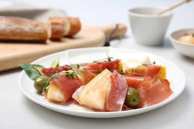 Plate with melon and prosciutto appetizer on light table