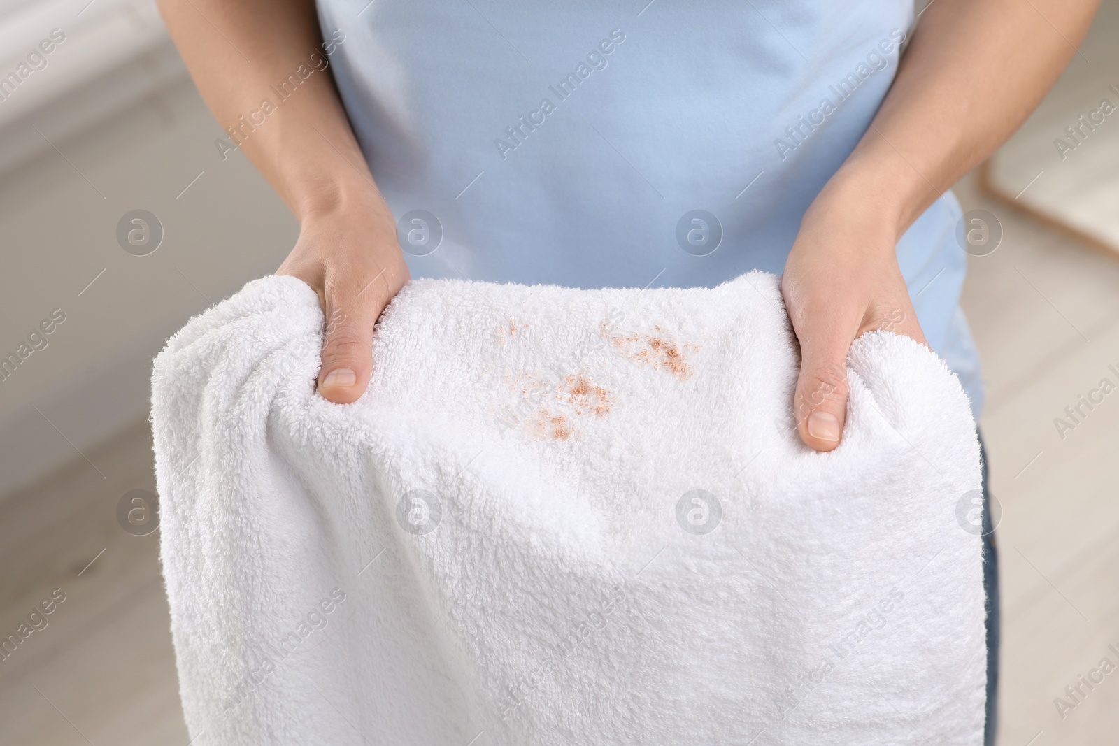 Photo of Woman holding terry towel with makeup spot indoors, closeup