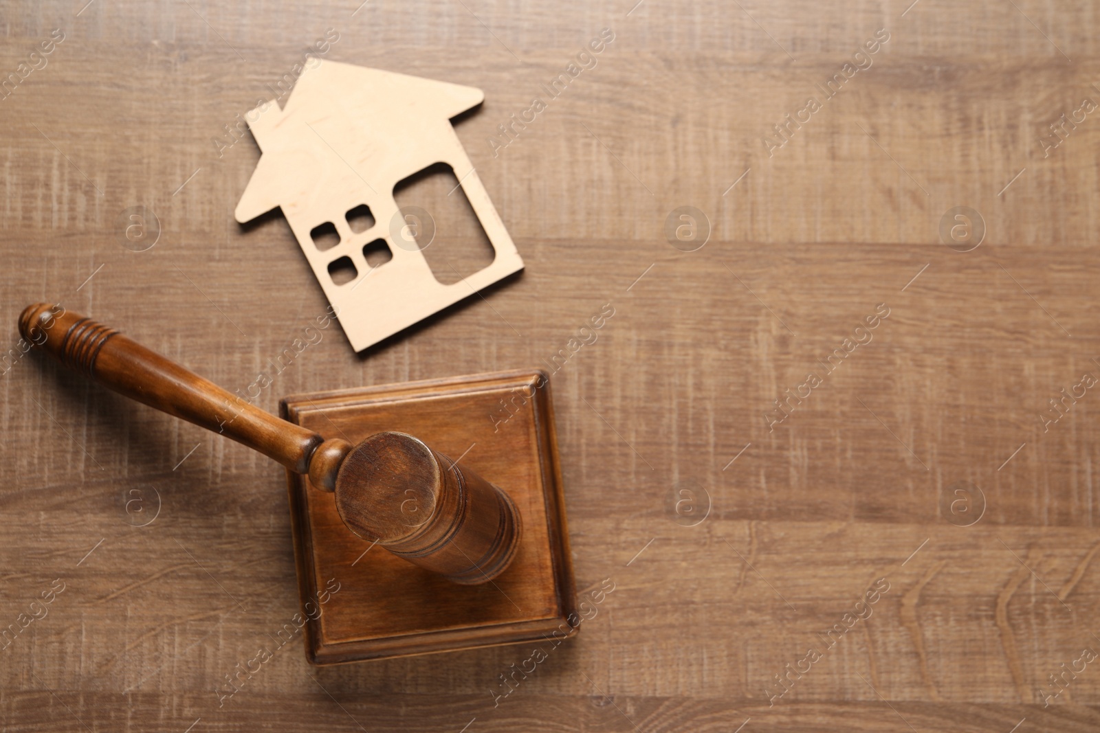 Photo of Law concept. Gavel and figure of house on wooden table, top view. Space for text