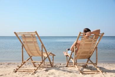 Young man relaxing in deck chair on sandy beach