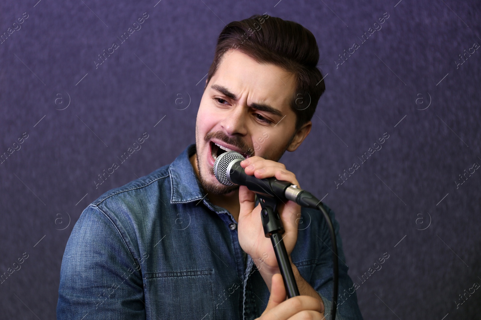 Photo of Young singer with microphone recording song in studio