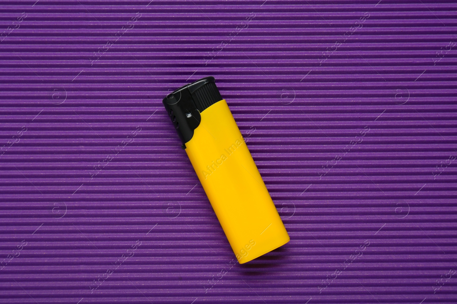 Photo of Stylish small pocket lighter on purple corrugated fiberboard, top view