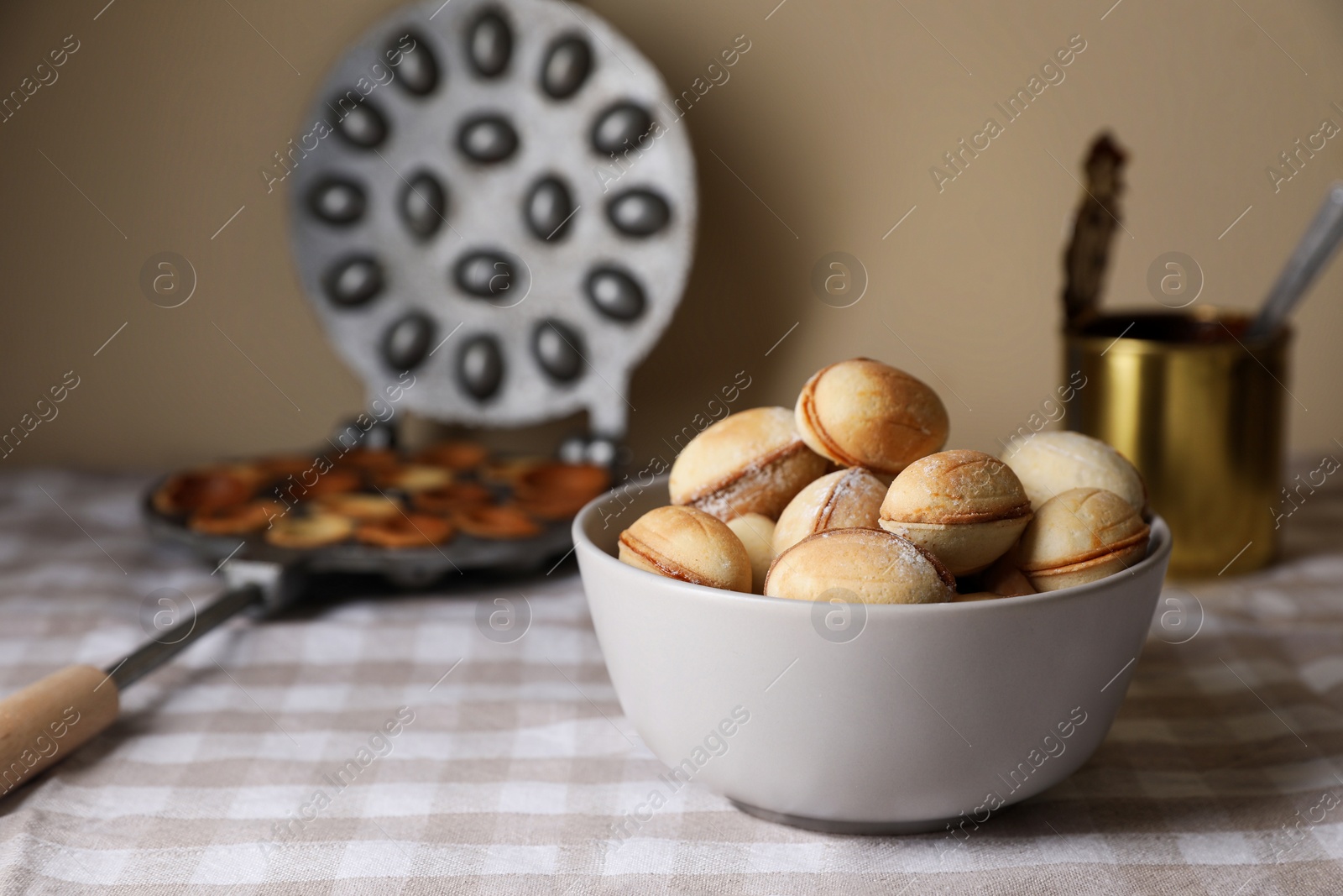 Photo of Bowl of delicious walnut shaped cookies with condensed milk on checkered tablecloth. Space for text