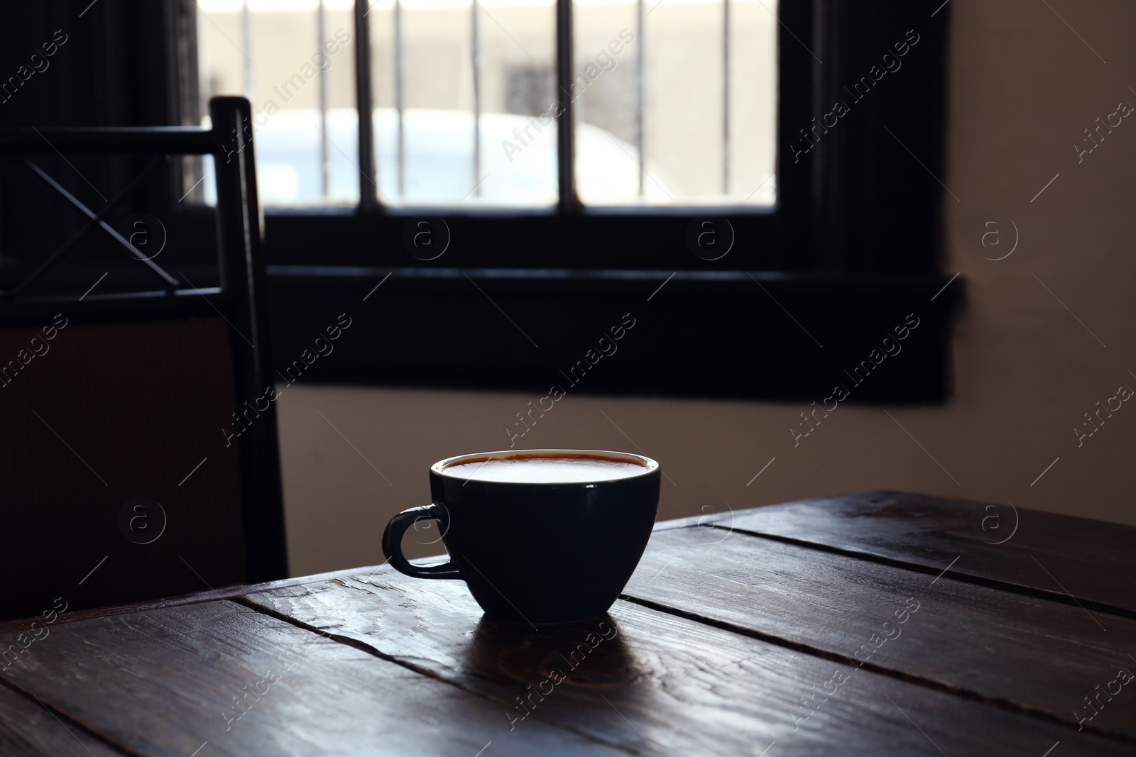 Photo of Cup of aromatic coffee on wooden table in cafe