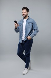 Photo of Happy young man using smartphone on grey background