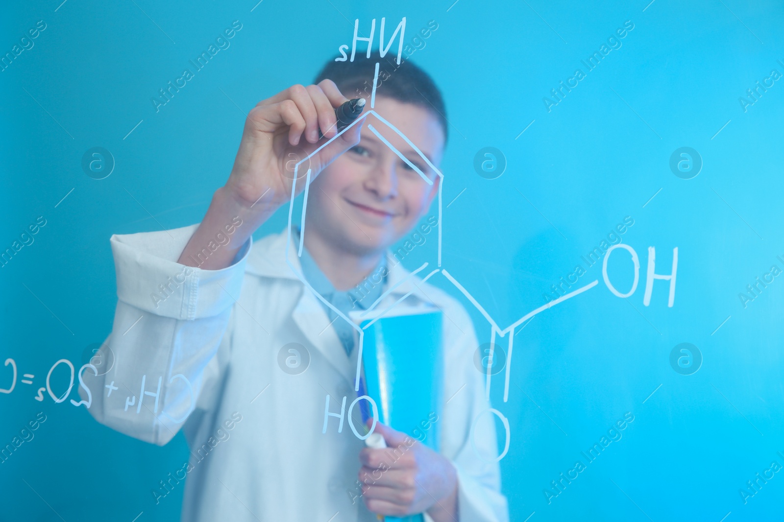 Photo of Schoolboy writing chemistry formula on glass board against color background. Space for text