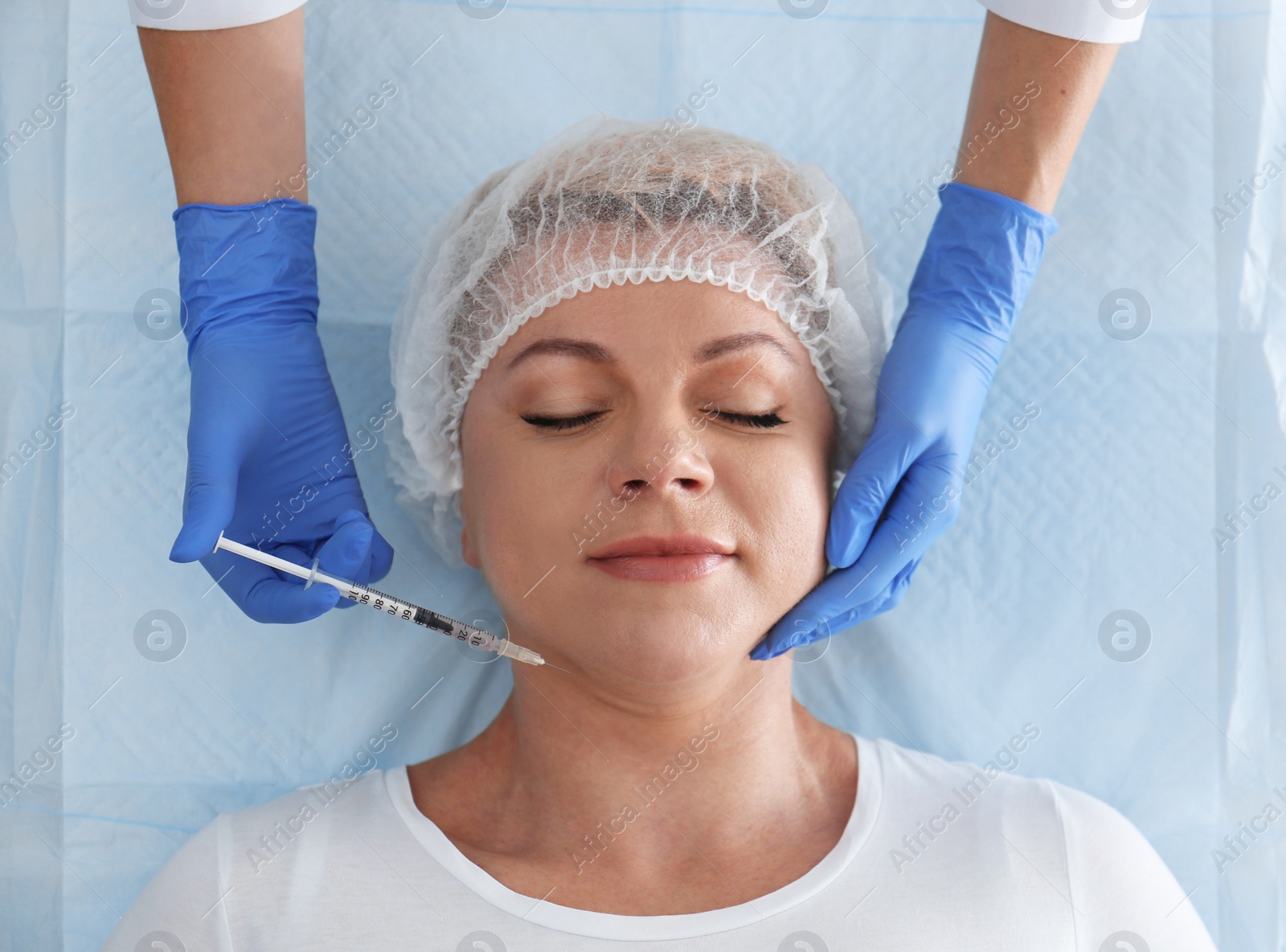 Photo of Mature woman with double chin receiving injection in clinic, above view