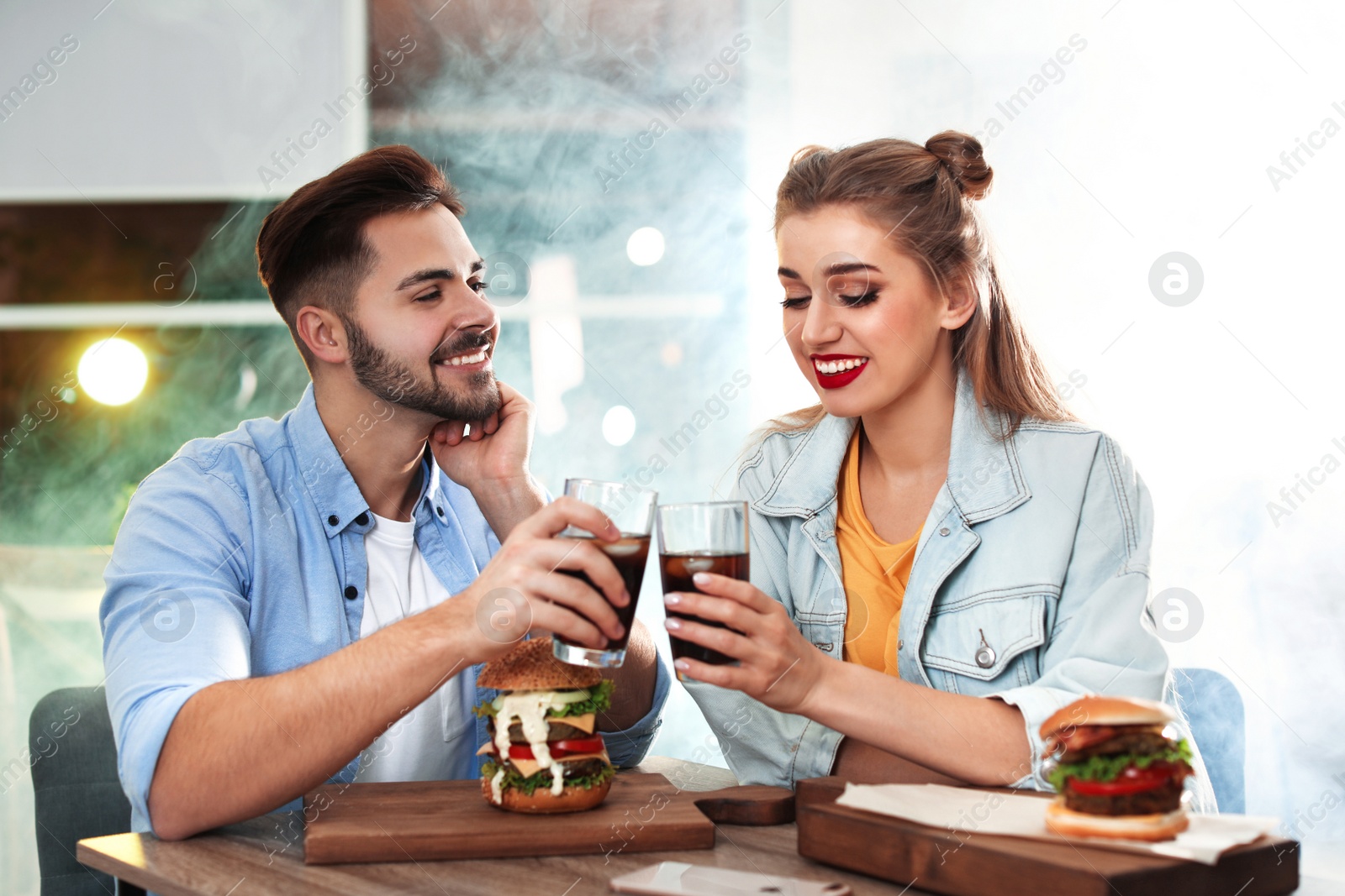 Photo of Happy young couple having lunch in burger restaurant