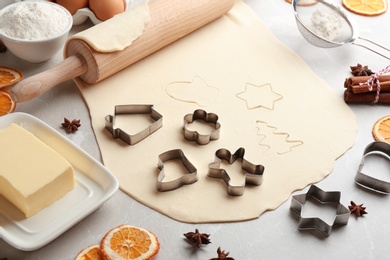 Photo of Making homemade Christmas cookies. Rolling pin, raw dough and cutters on grey table