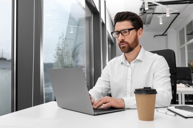 Photo of Man working on laptop at white desk in office. Space for text