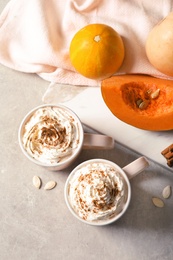 Flat lay composition with cups of tasty pumpkin spice latte on gray background