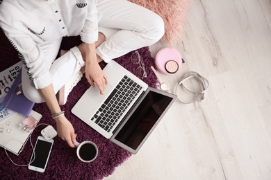 Female blogger with laptop and cup of coffee indoors, top view