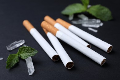Photo of Cigarettes, menthol crystals and mint on black background, closeup