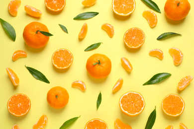 Photo of Flat lay composition with fresh ripe tangerines and leaves on light yellow background. Citrus fruit