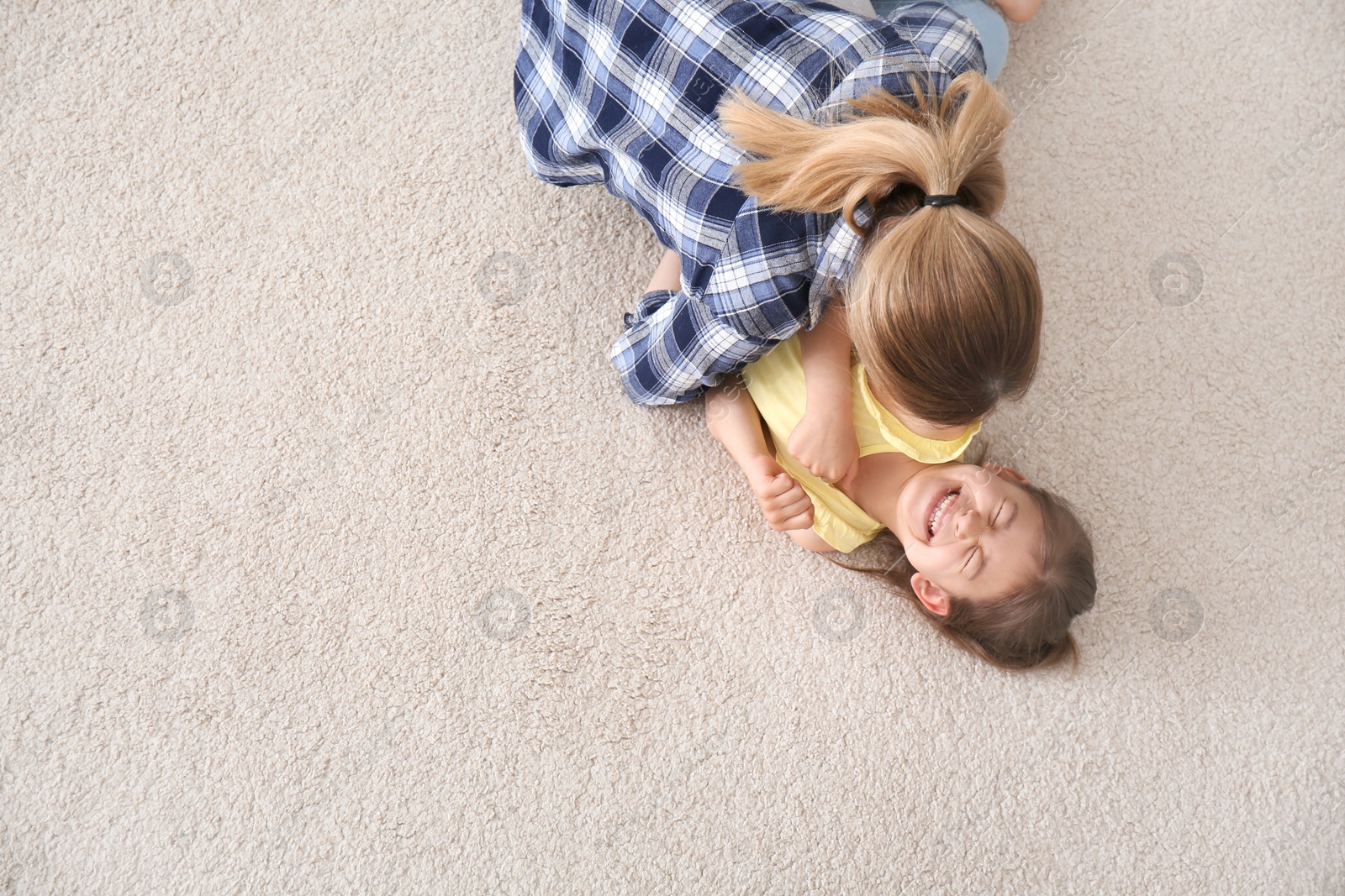 Photo of Cute little girl and her mother lying on cozy carpet at home