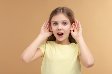 Little girl with hearing problem on pale brown background