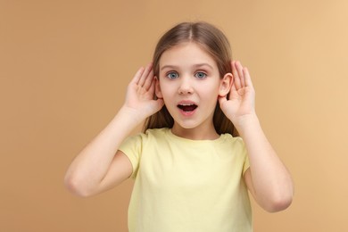 Photo of Little girl with hearing problem on pale brown background