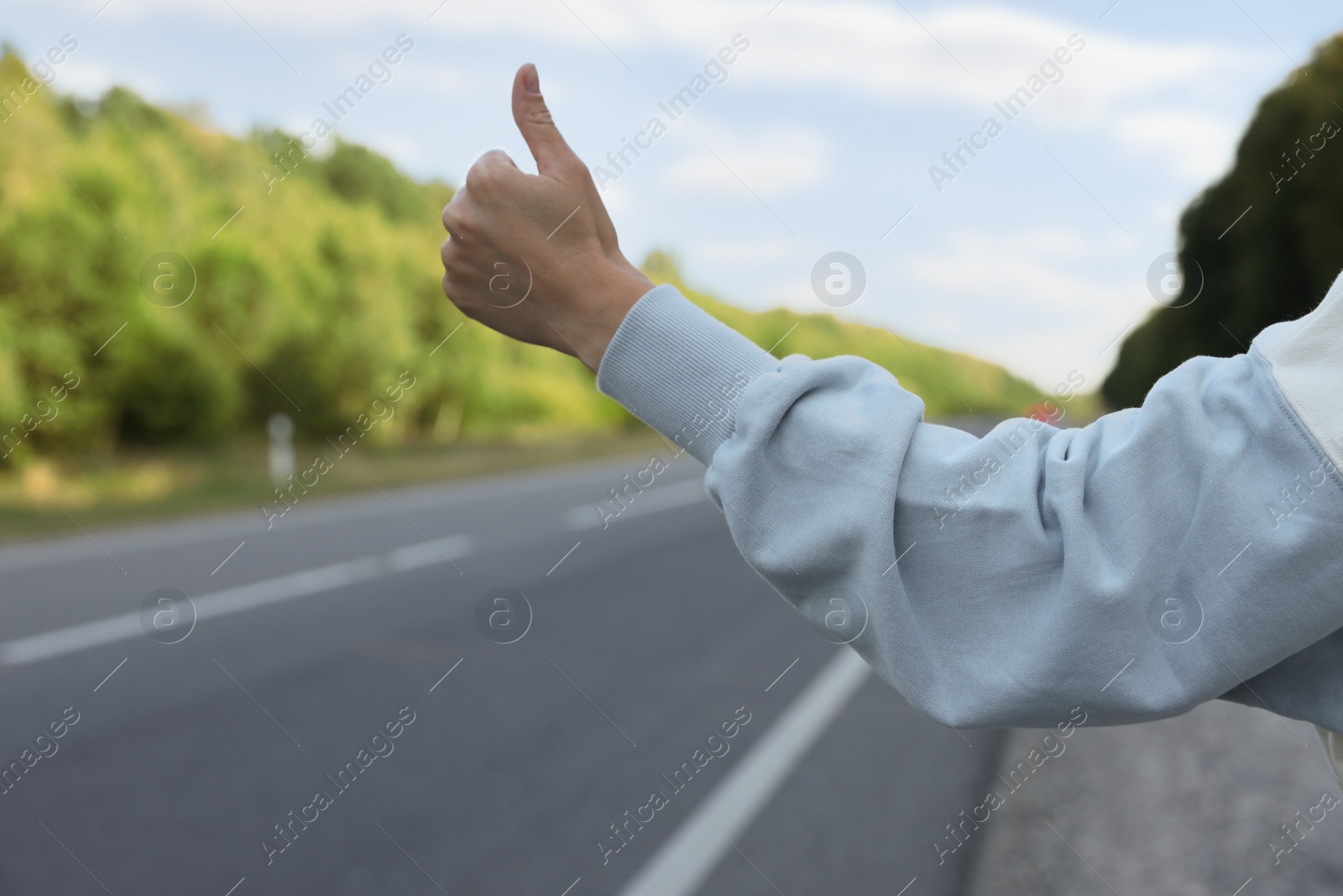 Photo of Woman catching car on road, closeup. Hitchhiking trip