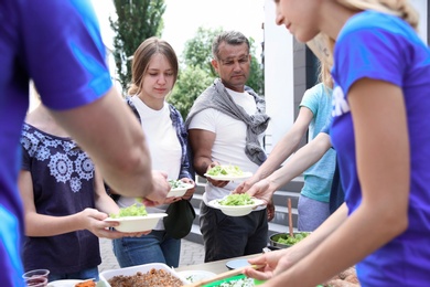 Volunteers serving food for poor people outdoors