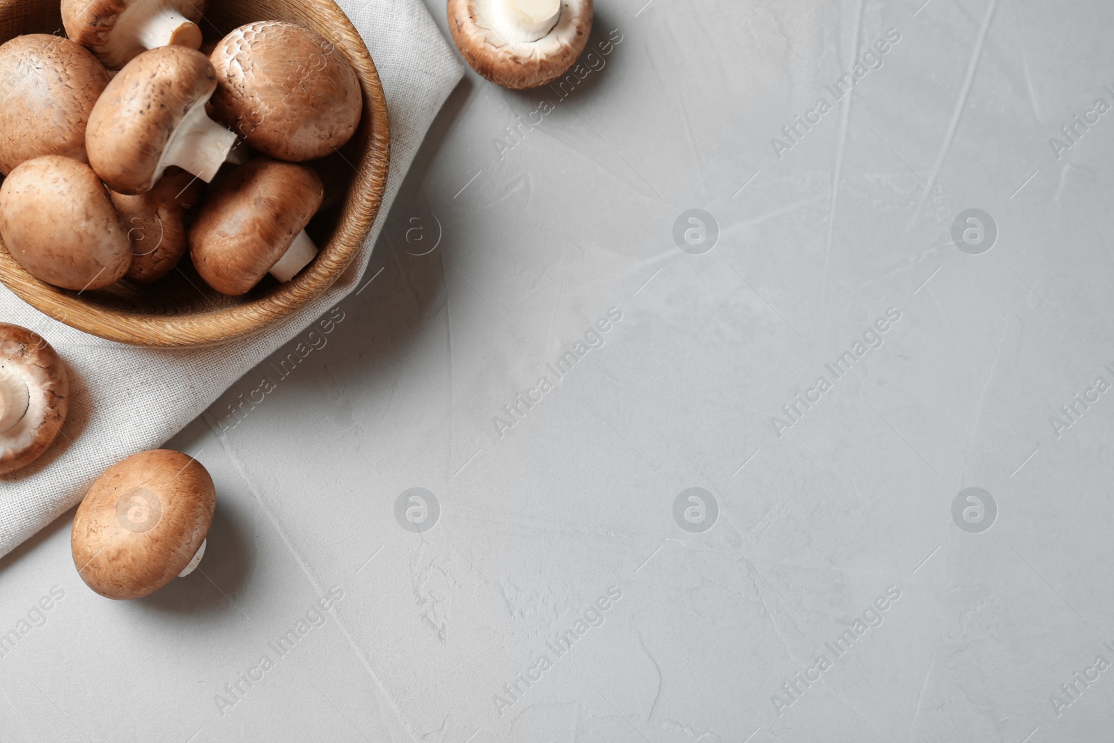 Photo of Fresh champignon mushrooms and wooden bowl on table, top view. Space for text