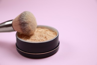 Face powder and brush on pink background, closeup. Space for text