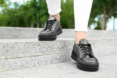 Photo of Woman wearing comfortable stylish shoes outdoors, closeup