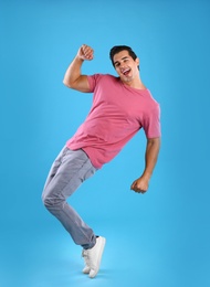 Photo of Handsome young man dancing on blue background