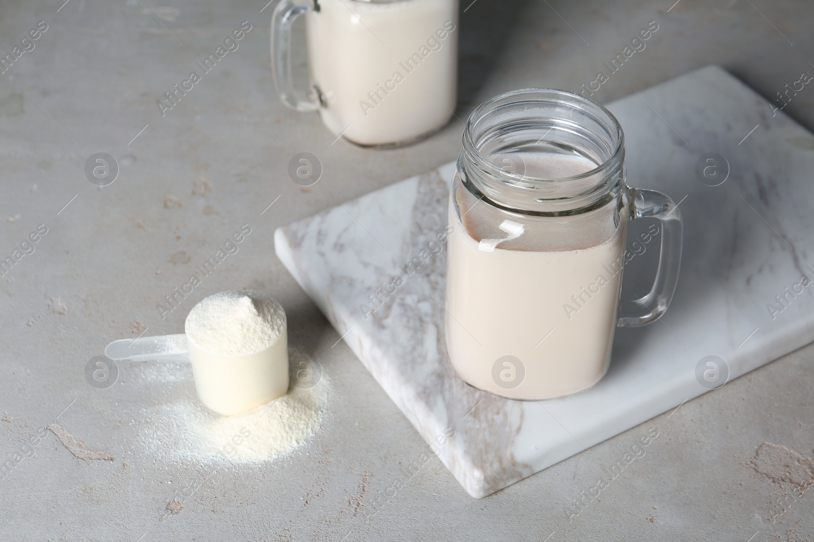 Photo of Mason jar with protein shake and scoop of powder on table