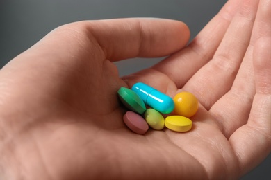 Woman holding weight loss pills on gray background, closeup