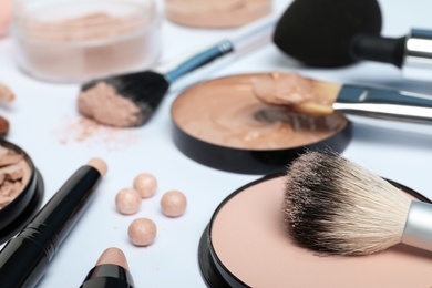 Composition with powder, skin foundation and beauty accessories on white background