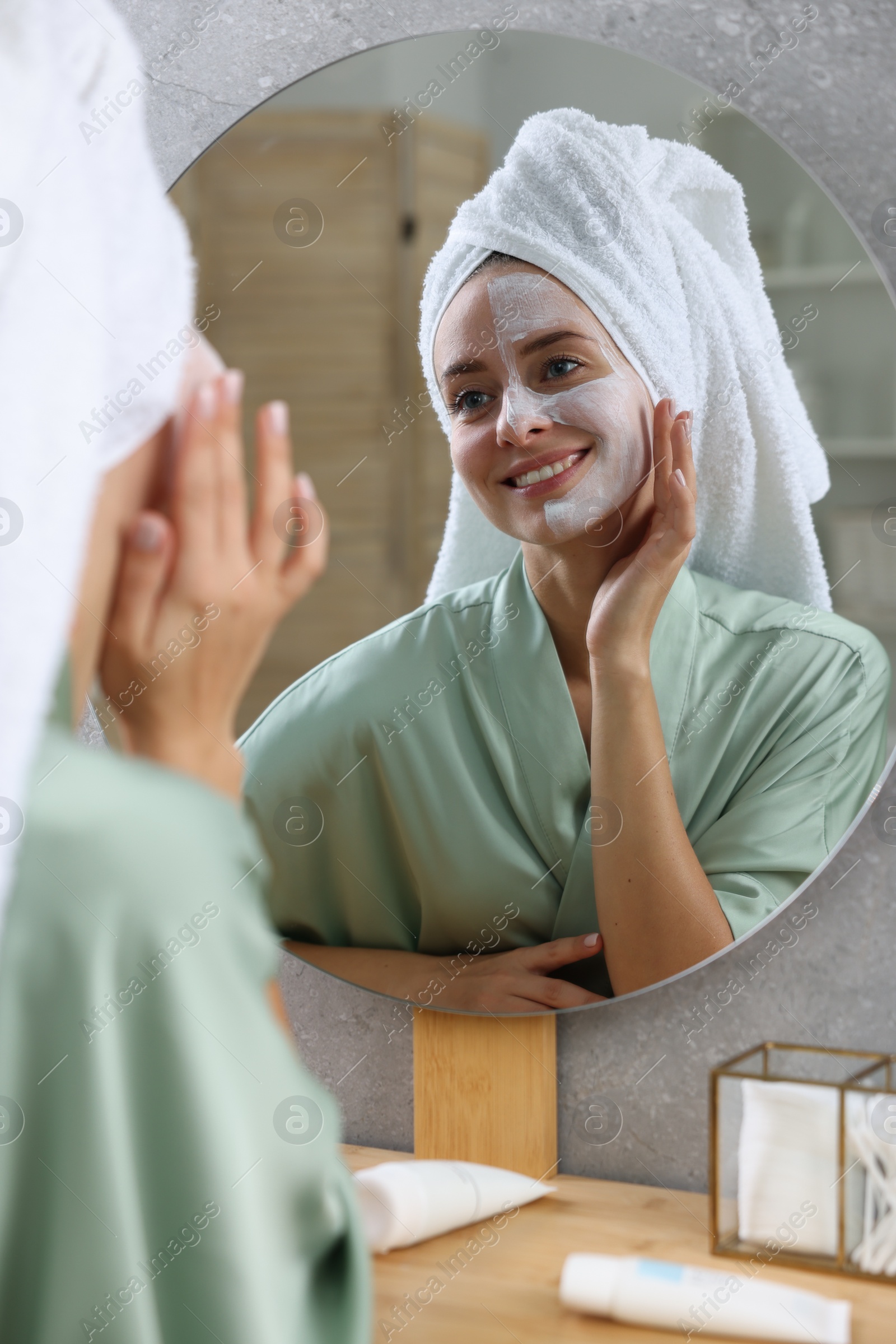 Photo of Woman with face mask near mirror in bathroom. Spa treatments