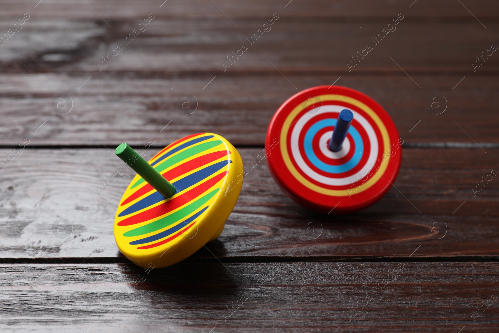 Photo of Bright spinning tops on wooden table, closeup