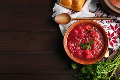 Photo of Stylish brown clay bowl with Ukrainian borsch served on wooden table, flat lay. Space for text