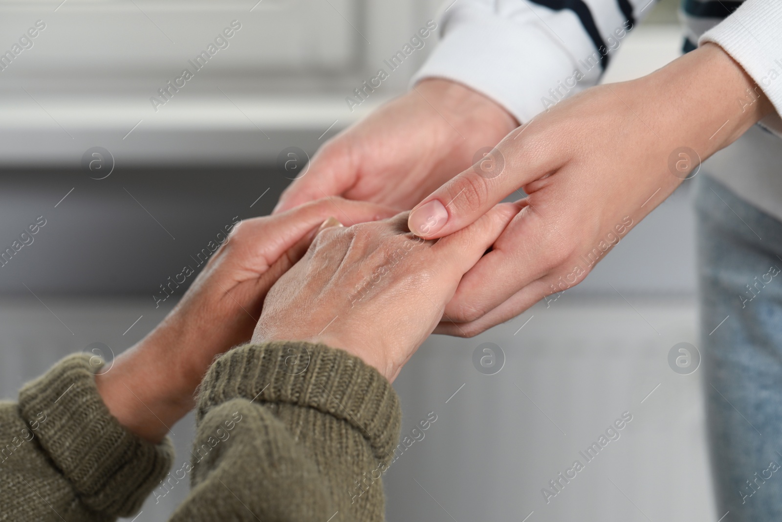 Photo of Caregiver helping elderly woman at home, closeup