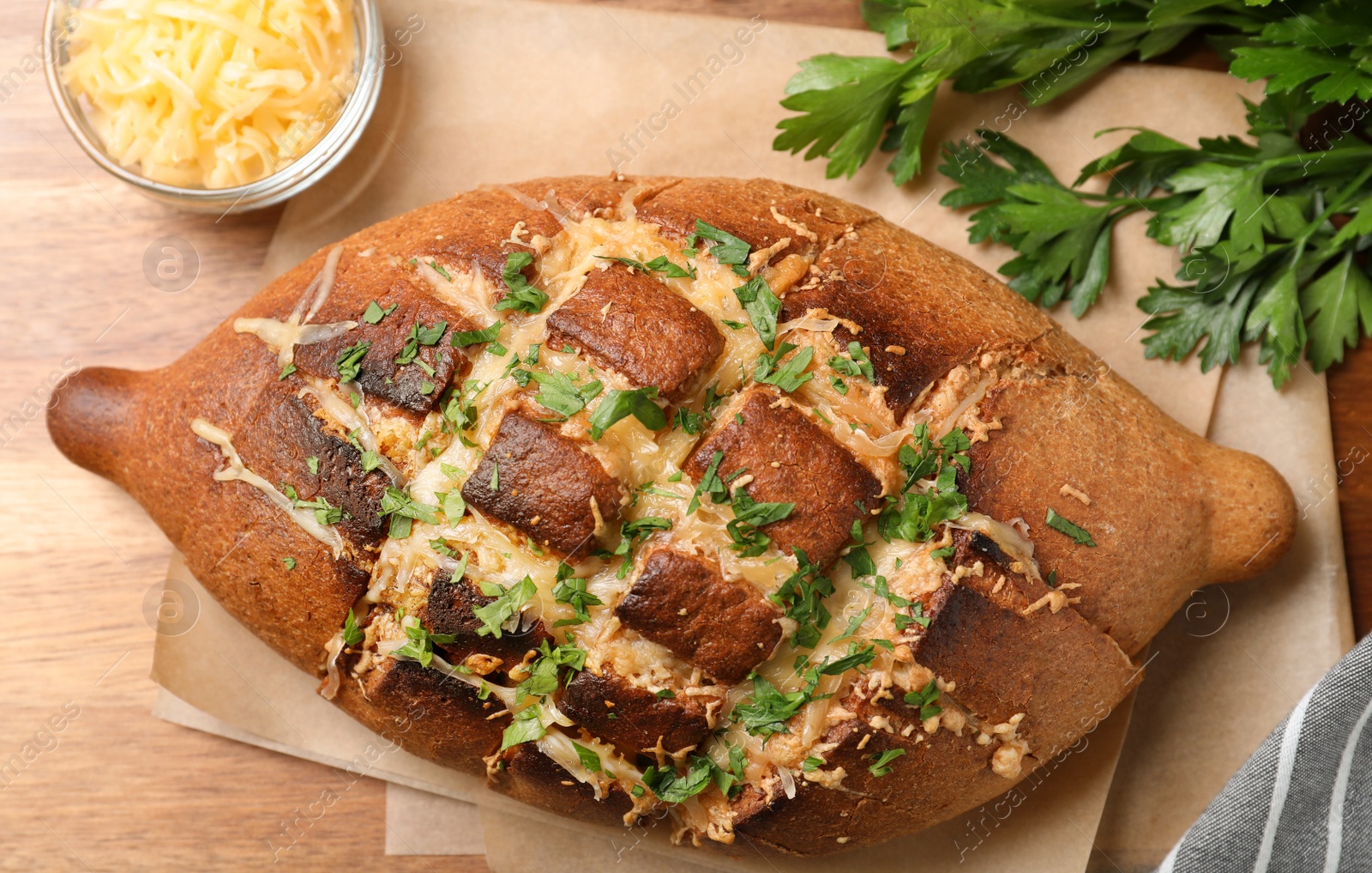 Photo of Delicious homemade garlic bread with herbs and cheese on wooden table, flat lay