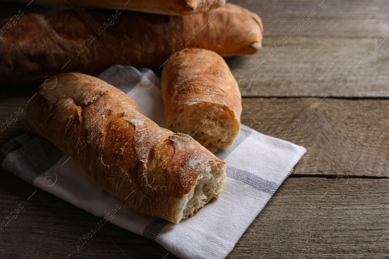 Photo of Fresh crispy ciabattas on wooden table, closeup