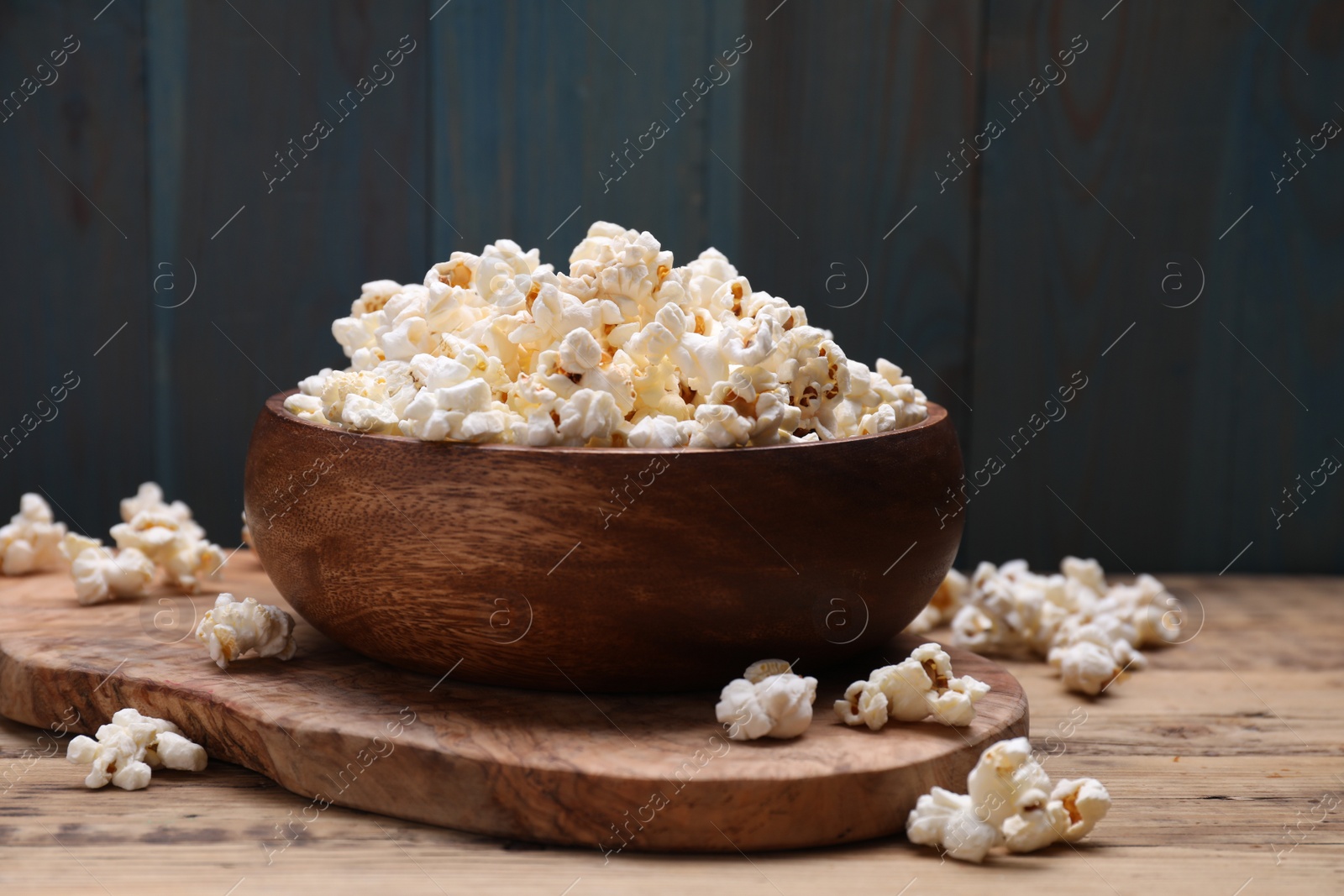 Photo of Bowl of tasty popcorn on wooden table