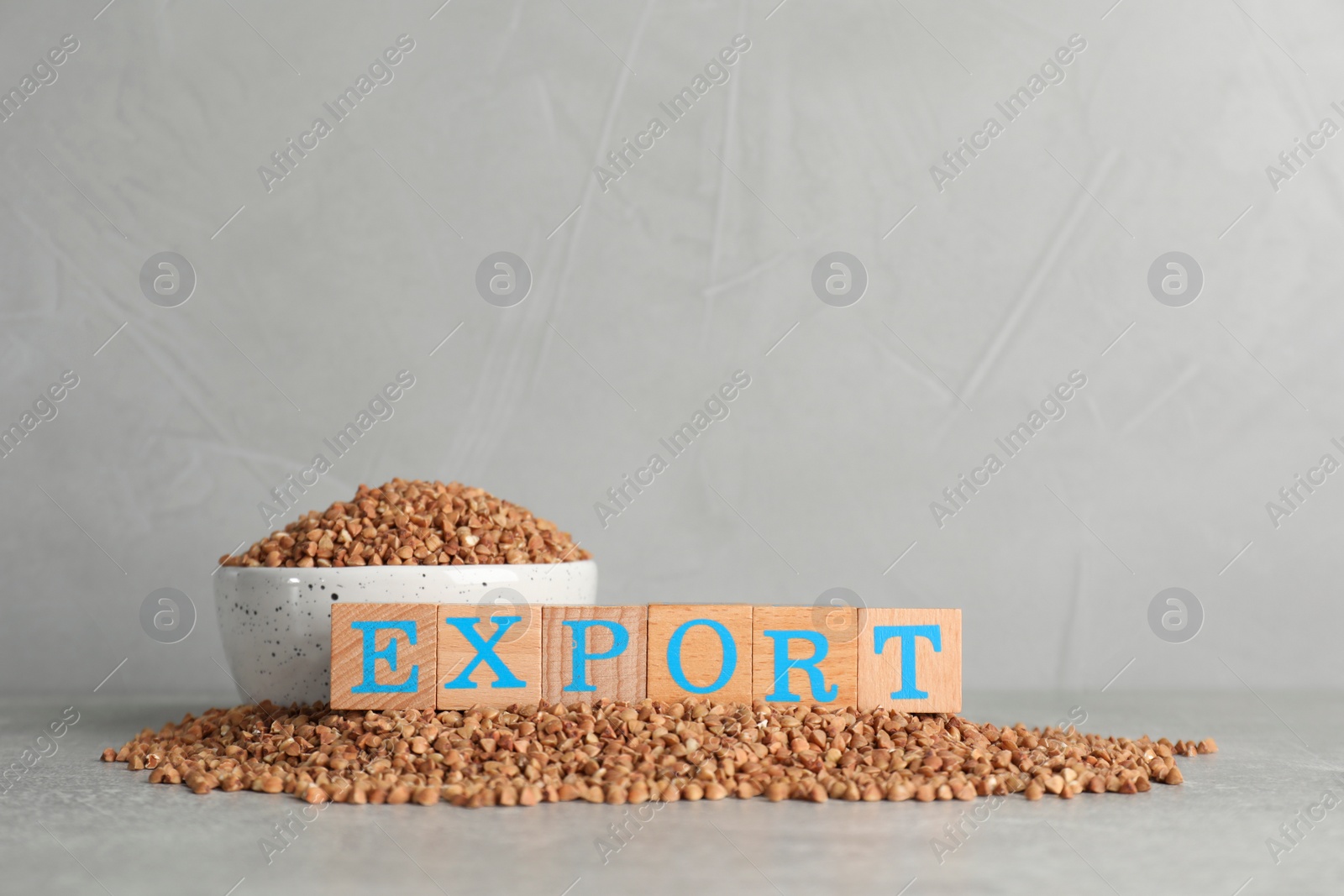 Photo of Word Export made of wooden cubes and buckwheat grains on grey background. Space for text