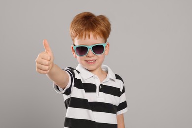 Photo of Cute little boy with sunglasses on light grey background